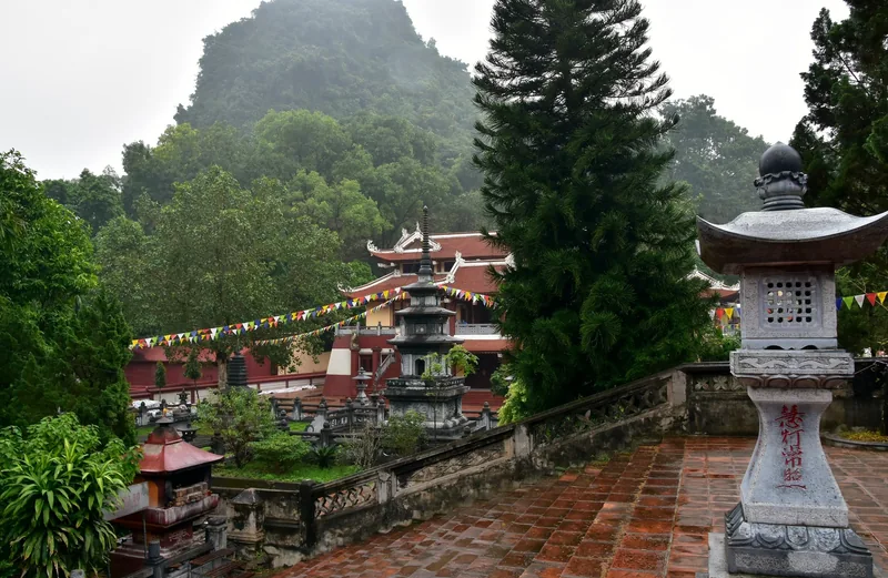 Đèn đá và các tháp mộ nhìn ra chùa Hương với núi đá vôi mờ sương phía sau, gần Hà Nội.