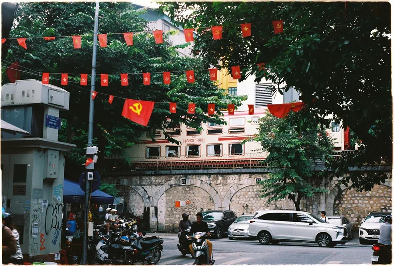 Cờ đỏ treo dưới cầu xe lửa khi xe máy và ô tô qua lại ở Phố Cổ Hà Nội.